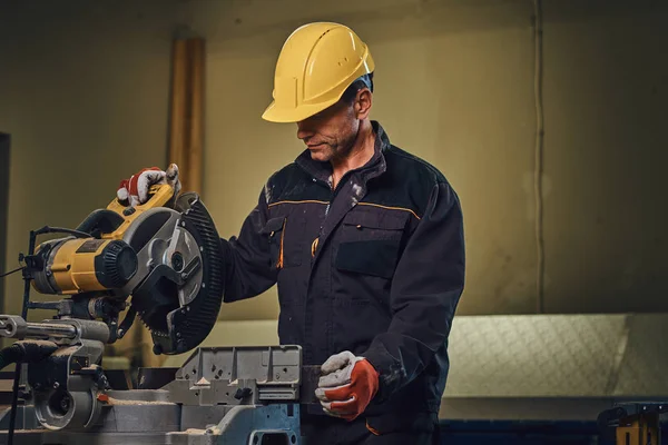 Sarı kap testere bir garajda çalışır bir emanet marangoz erkek giymiş.