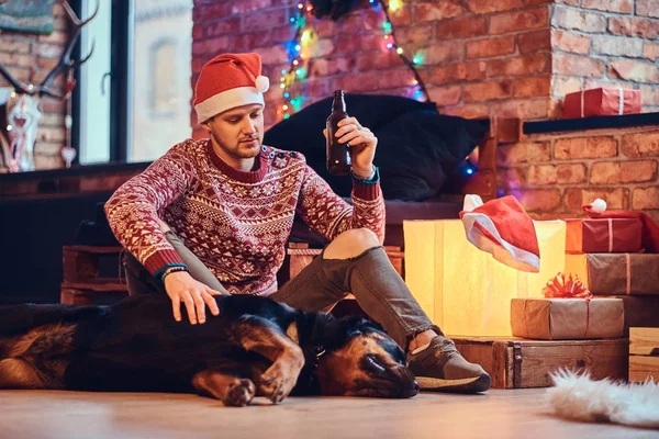有吸引力的长胡子的时髦男性坐在地板上与他的猎犬狗在一个房间里的圣诞装饰 — 图库照片
