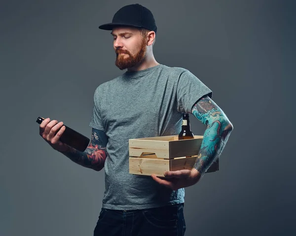 Portret Brodaty Mężczyzna Czapkę Tatuażami Ramiona Posiada Drewniane Pudełko Butelek — Zdjęcie stockowe
