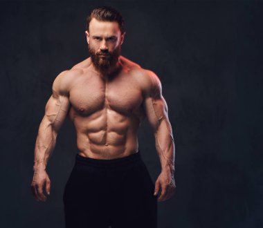 Sakallı gömleksiz vücut geliştirmeci gri arka plan üzerinde portresi.