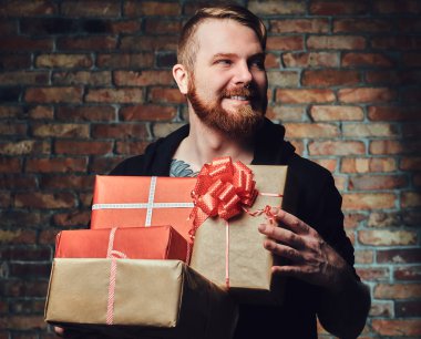 Pozitif Redbeard erkek Noel hediyeleri bir tuğla duvar üzerinde tutar..