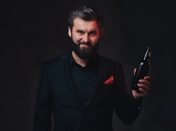 A stylish bearded male dressed in a black suit presenting craft beer.