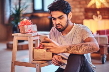 Hint rahat sakallı erkek Noel dekorasyonu ile çatı odasında bir smartphone kullanarak.