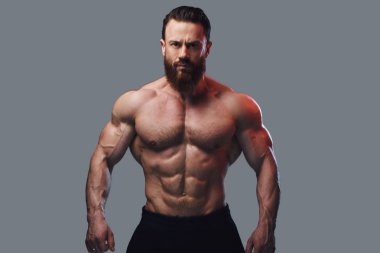 Sakallı gömleksiz vücut geliştirmeci gri arka plan üzerinde portresi.