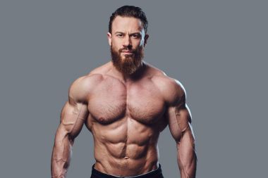 Sakallı gömleksiz vücut geliştirmeci gri arka plan üzerinde portresi.