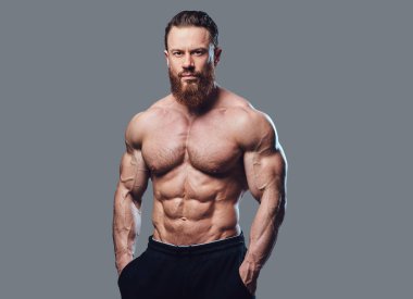 Sakallı gömleksiz vücut geliştirmeci gri arka plan üzerinde portresi.