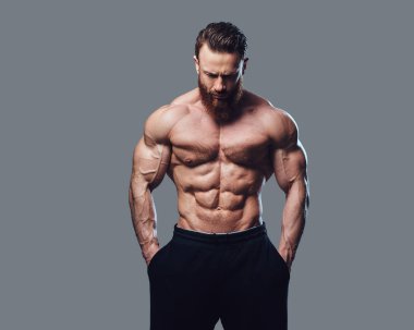 Sakallı gömleksiz vücut geliştirmeci gri arka plan üzerinde portresi.