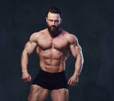 Sakallı gömleksiz vücut geliştirmeci gri arka plan üzerinde portresi.