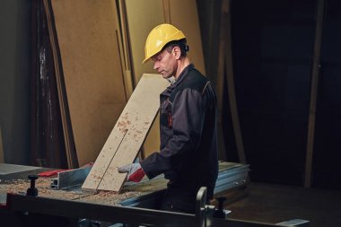 Sarı kap testere bir garajda çalışır bir emanet marangoz erkek giymiş.