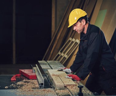 Sarı kap testere bir garajda çalışır bir emanet marangoz erkek giymiş.