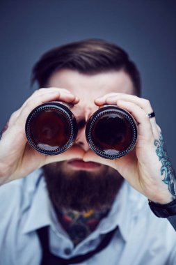 Bira şişeleri ile bakan birisi.