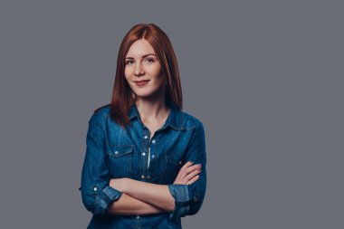 Gri arka plan üzerinde bir kot gömlek giymiş bir gezgin Kızıl saçlı kadın portresi.