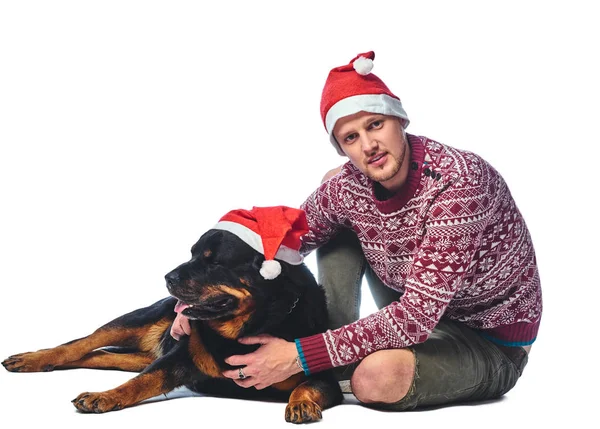 Mężczyzna Ubrany Sweter Wełniany Santa Hat Jego Pies Rottweiler Białym — Zdjęcie stockowe