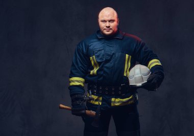 Stüdyo portre üniformalı bir itfaiye eri ve balta tutar.