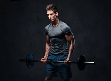 Atletik erkek pazı halter egzersiz. Stüdyo portre gri arka plan üzerinde.