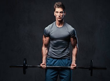 Atletik erkek pazı halter egzersiz. Stüdyo portre gri arka plan üzerinde.