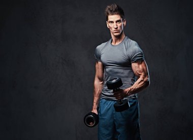 Atletik erkek pazı dumbbell egzersiz. Stüdyo portre gri arka plan üzerinde.