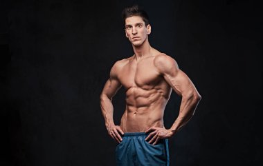 Stüdyo portre ectomorph kas gömleksiz erkek koyu gri arka plan üzerinde.