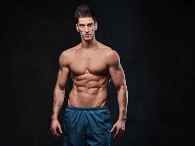 Stüdyo portre ectomorph kas gömleksiz erkek koyu gri arka plan üzerinde.