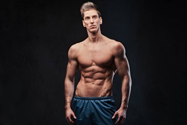 Stüdyo portre ectomorph kas gömleksiz erkek koyu gri arka plan üzerinde.