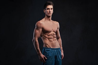 Stüdyo portre ectomorph kas gömleksiz erkek koyu gri arka plan üzerinde.