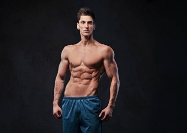 Stüdyo portre ectomorph kas gömleksiz erkek koyu gri arka plan üzerinde.