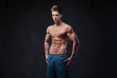 Stüdyo portre ectomorph kas gömleksiz erkek koyu gri arka plan üzerinde.