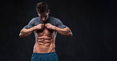 Stüdyo portre ectomorph kas gömleksiz erkek göğüs kasları koyu gri arka plan üzerinde gösterir..