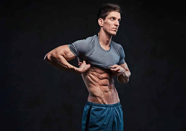 痩せ型の人の筋肉の上半身裸の男性のスタジオ ポートレートが シャツを脱ぐし 暗い灰色の背景の上の胸の筋肉を示しています — ストック写真