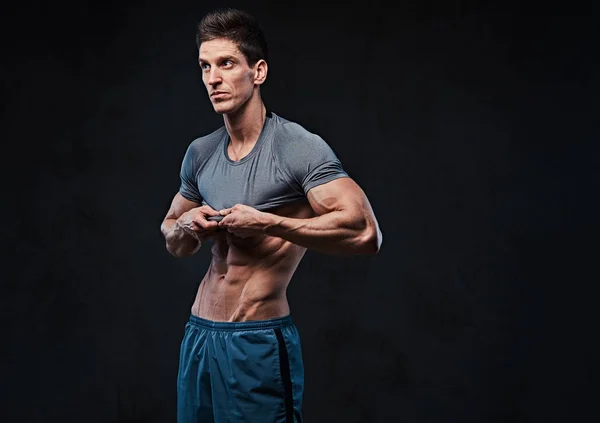 痩せ型の人の筋肉の上半身裸の男性のスタジオ ポートレートが シャツを脱ぐし 暗い灰色の背景の上の胸の筋肉を示しています — ストック写真