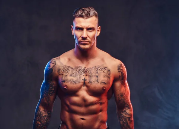 A muscular tattooed man on a dark background. — Stock Photo, Image