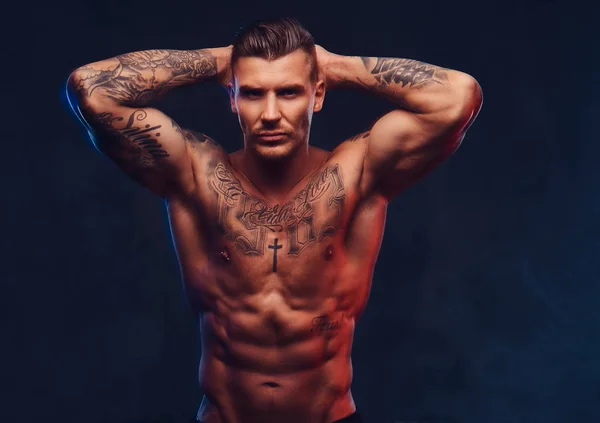 Un bărbat tatuat muscular pe fundal întunecat . — Fotografie, imagine de stoc