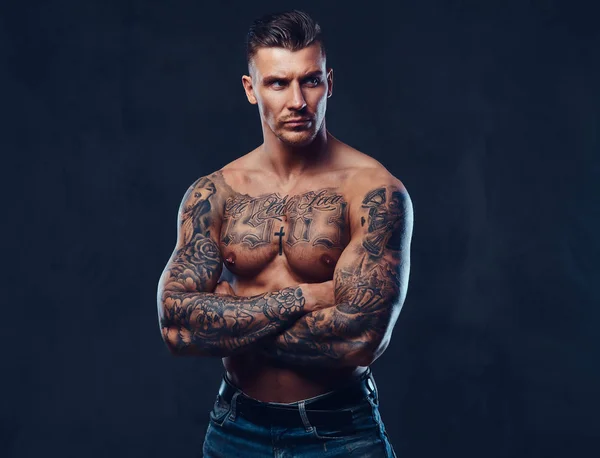 En muskulös tatuerad man över mörk bakgrund. — Stockfoto