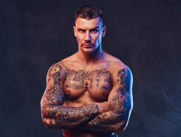 A muscular tattooed man over dark background. — Stock Photo, Image