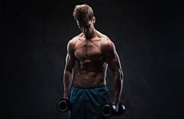 Atletik gömleksiz erkek pazı dumbbell egzersiz koyu gri kağıt üzerinde.