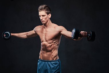 Gömleksiz atletik erkek yapıyor dumbbells ile yanal baş egzersizler omuzlar.