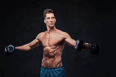 Gömleksiz atletik erkek yapıyor dumbbells ile yanal baş egzersizler omuzlar.