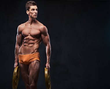 Gömleksiz atletik ectomorph erkek halter ağırlık kollarında tutar..