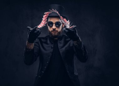 İskambil ile hüner karanlık bir arka plan üzerinde gösterilen sihirbaz siyah bir takım elbise, güneş gözlüğü ve şapka,.