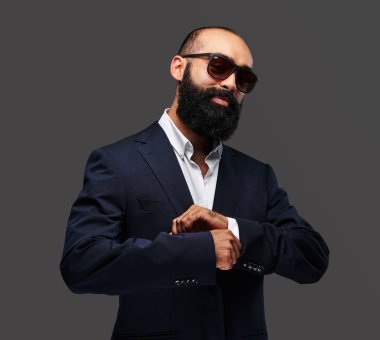 Şık bir takım elbise ve güneş gözlüğü sakallı bir erkek portresi stüdyo.