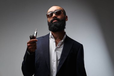 Siyah bir takım elbise ile elektronik bir boru sakallı bir işadamı portresi stüdyo.