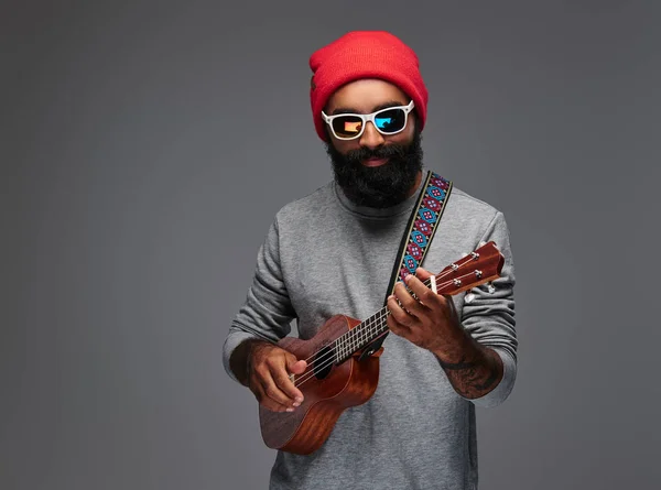 Retrato Homem Hipster Barbudo Chapéu Vermelho Óculos Sol Jogando Ukulele — Fotografia de Stock