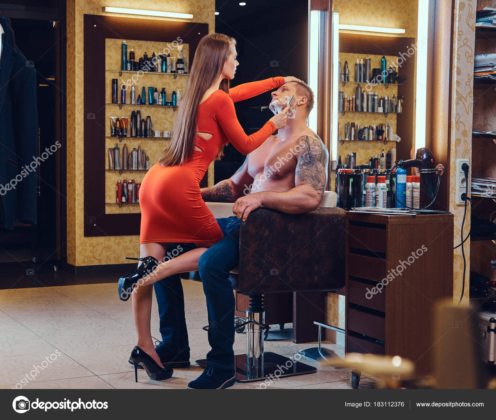 Hot and sexy female hairdresser shaving with straight razor a shirtless  athletic male in a barber shop. — Photo