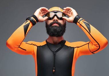 Turuncu neopren dalgıç elbisesi ve gri arka plan üzerinde izole dalış maske sakallı bir erkek portresi.