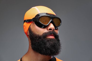 Yakın çekim turuncu neopren dalgıç elbisesi ve gri arka plan üzerinde izole dalış maske sakallı bir erkek portresi.