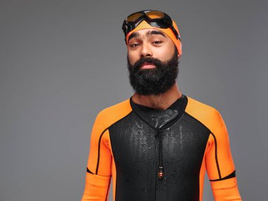 Turuncu neopren dalgıç elbisesi ve gri arka plan üzerinde izole dalış maske sakallı bir erkek portresi.