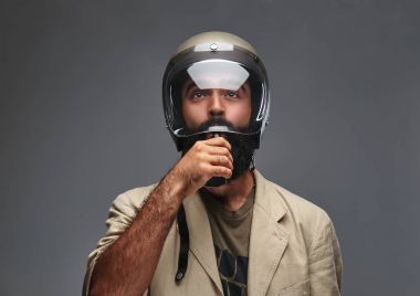 Bir motosiklet kask sigara elektronik sigara içinde sakallı hippi. Gri bir arka plan üzerinde izole.