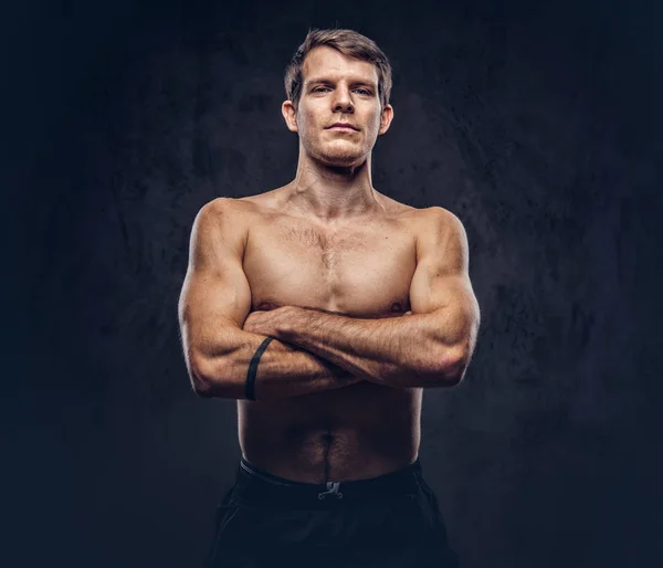 A shirtless handsome athletic male posing over dark background.