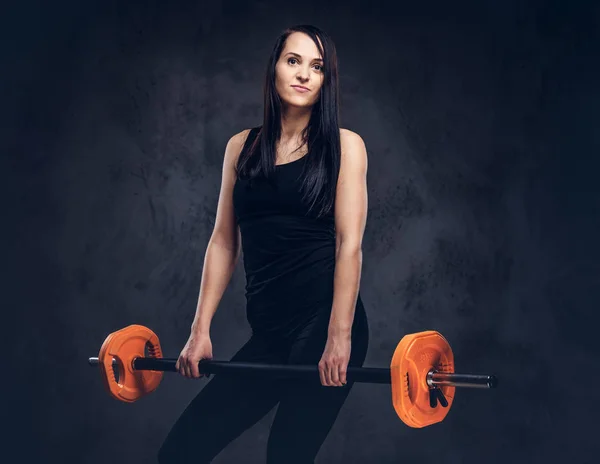 Sportowa Fitness Brunetka Kobieta Stwarzających Sztangą Studio Szary Tło — Zdjęcie stockowe