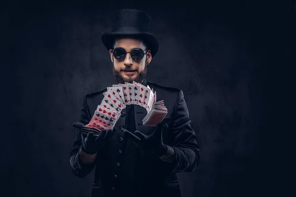 魔术师在黑色的西装 太阳镜和顶帽子 显示在黑暗背景下打牌的把戏 — 图库照片